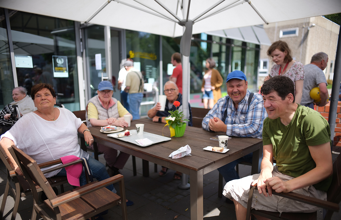 Gruppe Bürger:innen sitzen unter einem Sonnenschirm am Tisch in Neuerkerode