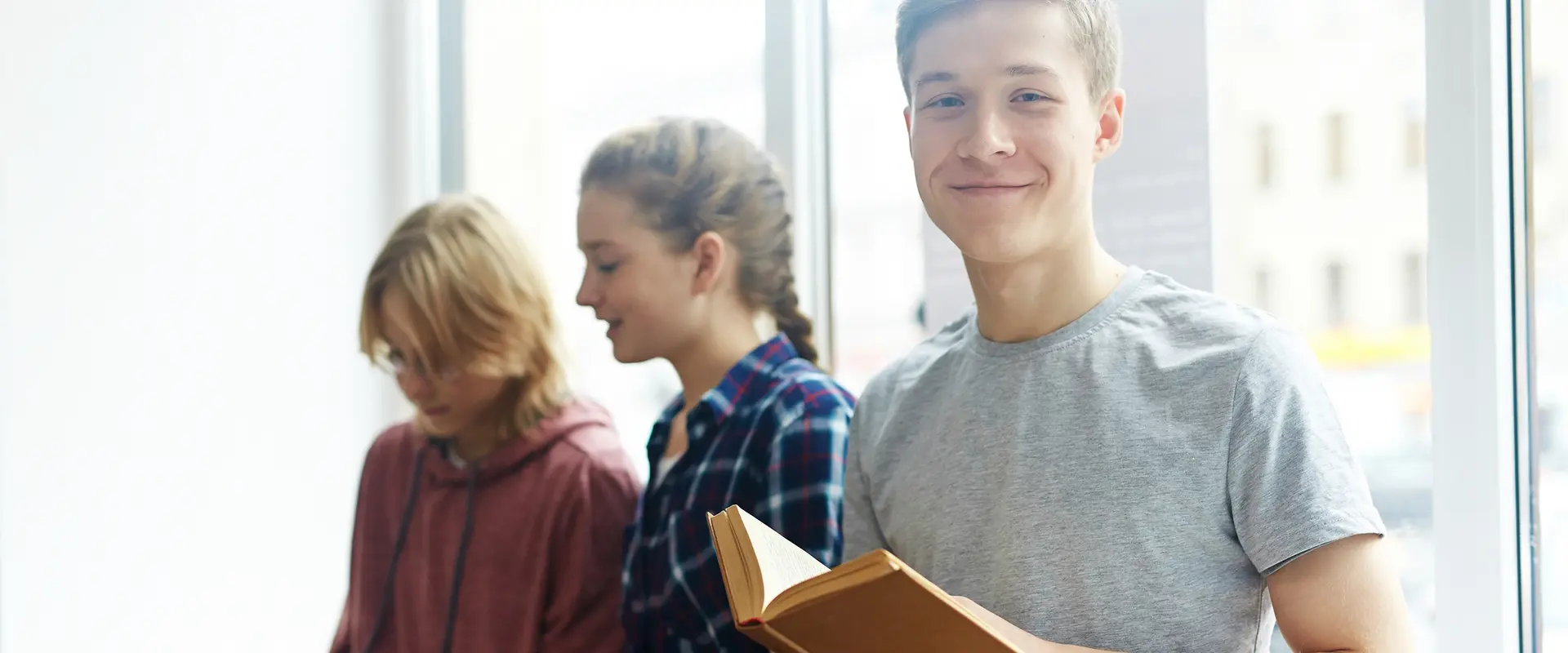 junge Menschen sitzen auf einer Fensterbank und schauen in Bücher