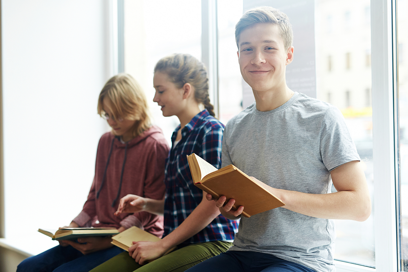 junge Menschen sitzen auf einer Fensterbank und schauen in Bücher